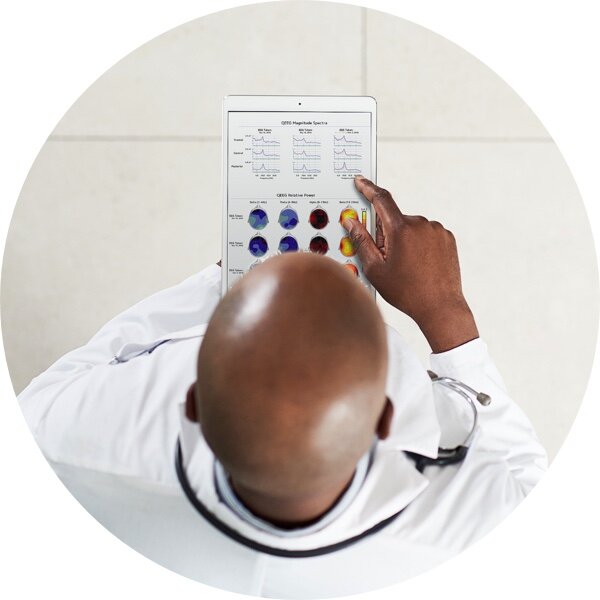 A clinician reviewing qEEG analysis results on a tablet